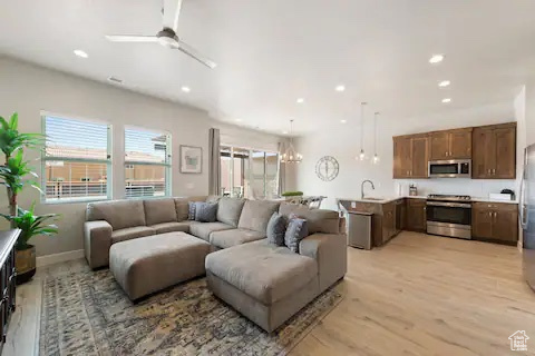 Living room featuring light hardwood / wood-style floors, sink, and ceiling fan with notable chandelier