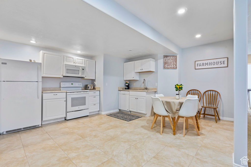 Kitchen featuring sink, white cabinetry, white appliances, and light tile patterned floors