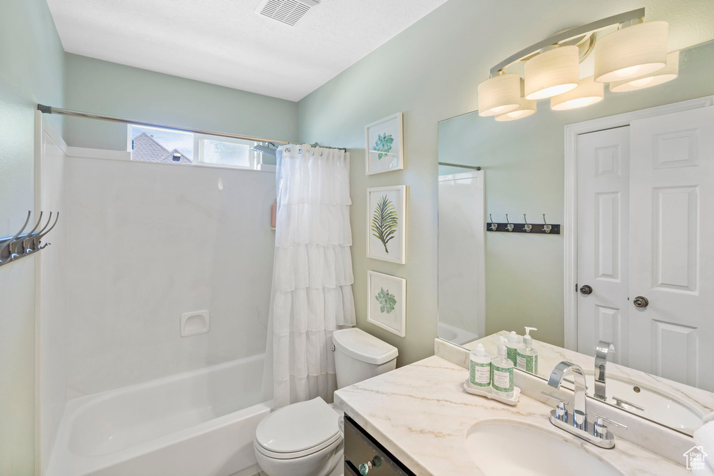 Full bathroom featuring vanity, shower / bath combo, and toilet