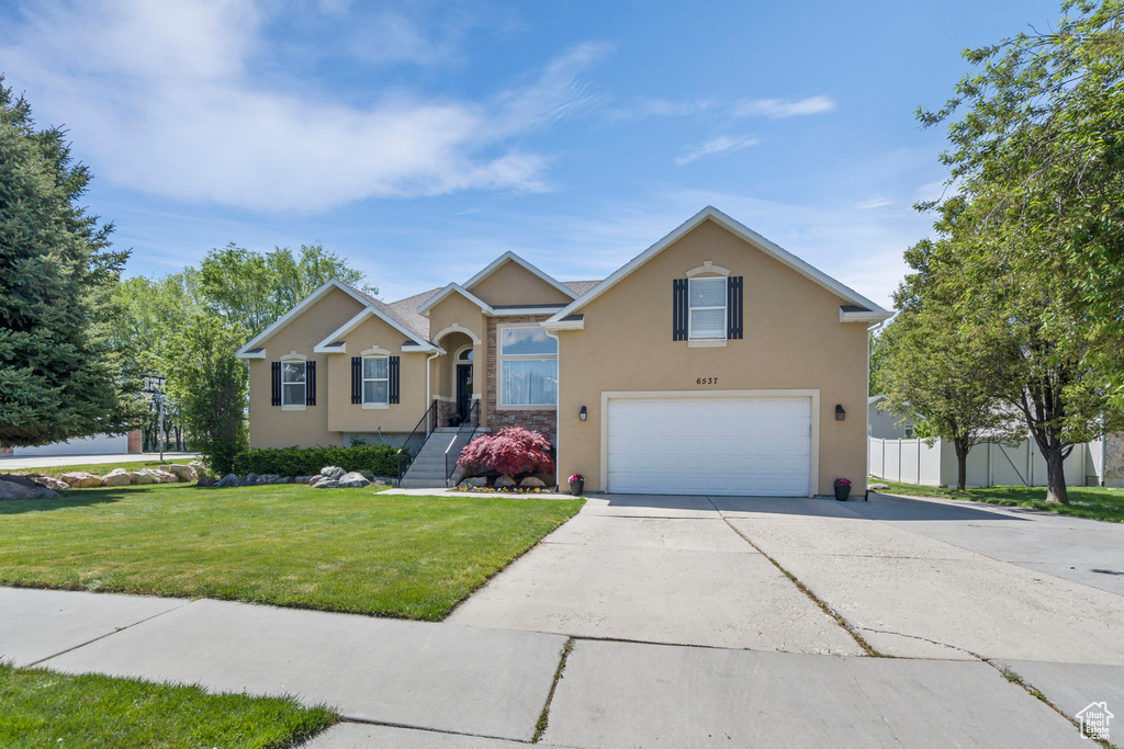 View of front of property featuring a garage and a front lawn