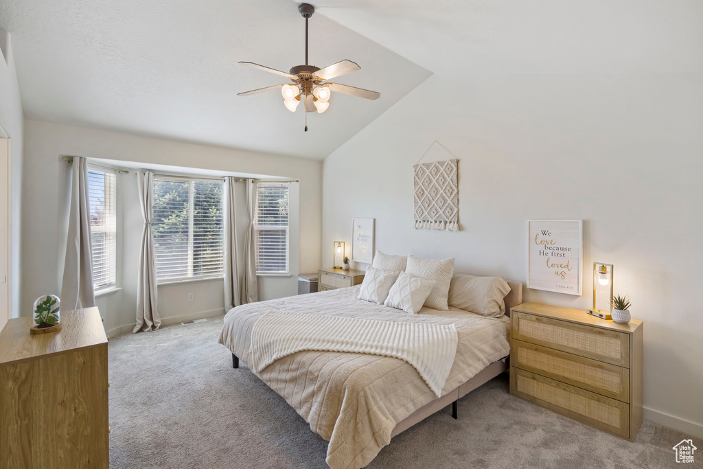 Carpeted bedroom featuring ceiling fan and vaulted ceiling