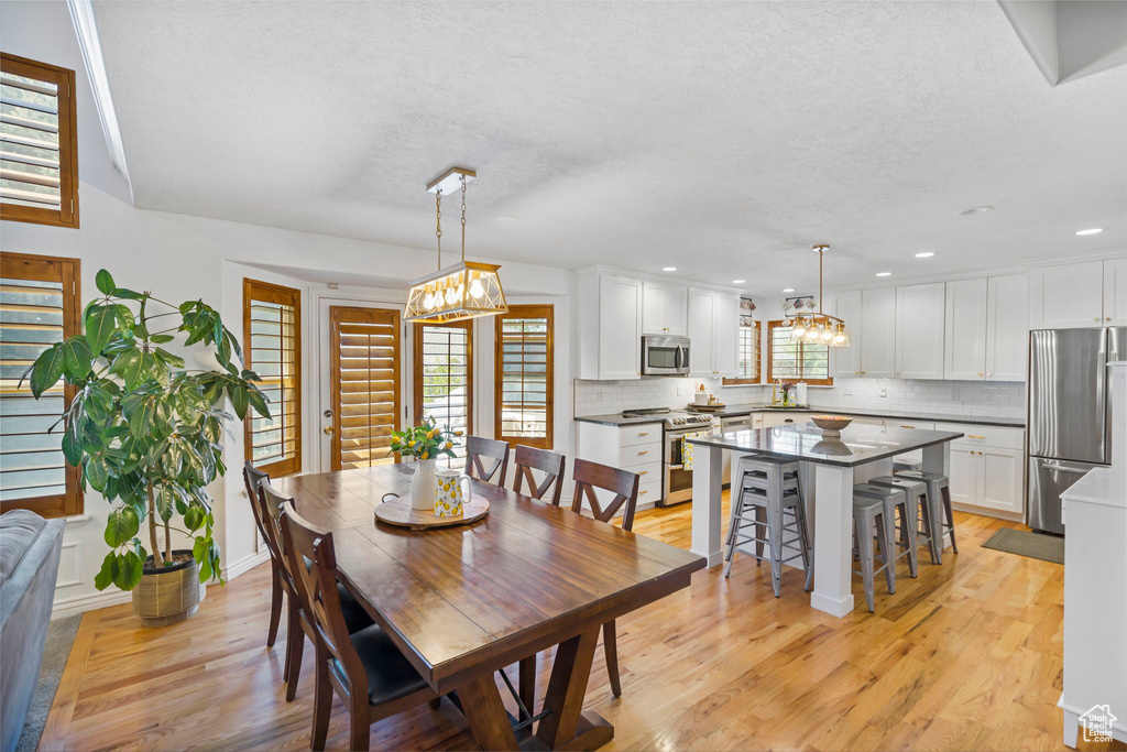 Dining area with sink, a notable chandelier, and light hardwood / wood-style floors