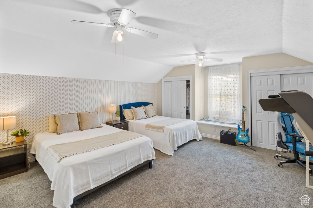 Carpeted bedroom featuring multiple closets, lofted ceiling, and ceiling fan