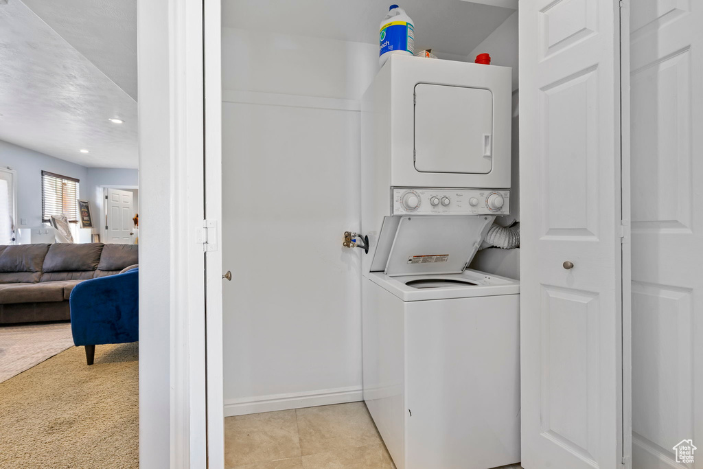 Laundry area featuring light carpet and stacked washer and dryer