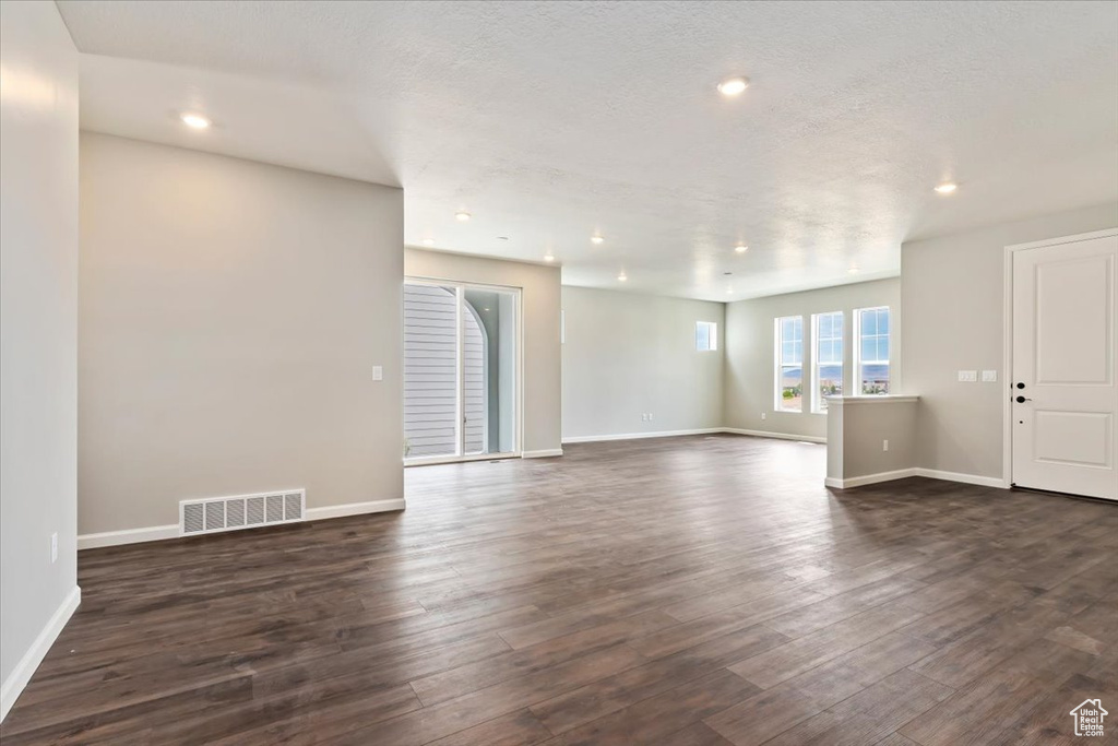 Unfurnished living room featuring dark hardwood / wood-style floors and a textured ceiling