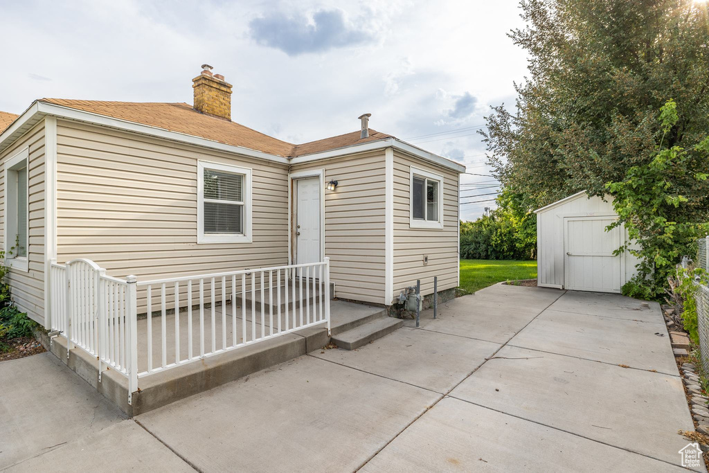 Back of property featuring a storage unit and a patio area