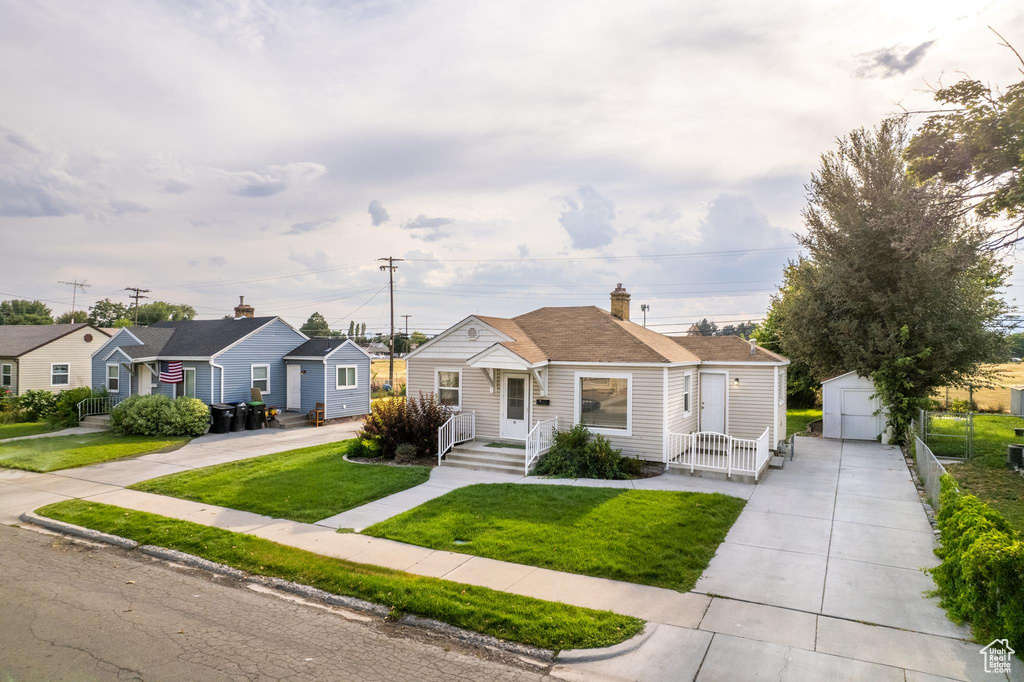 View of front of home featuring a garage, a front lawn, and an outdoor structure