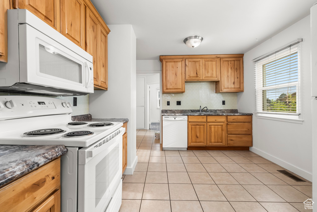 Kitchen with dishwasher, dark stone countertops, stove, and sink