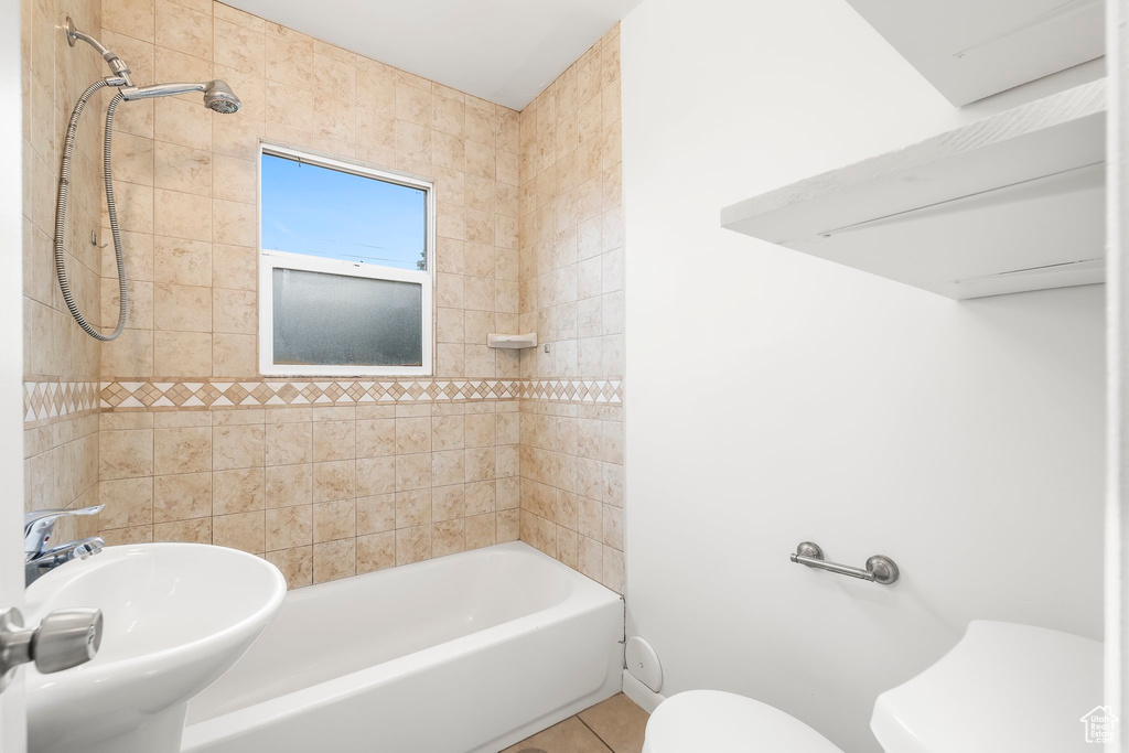 Full bathroom featuring tile patterned flooring, toilet, sink, and tiled shower / bath