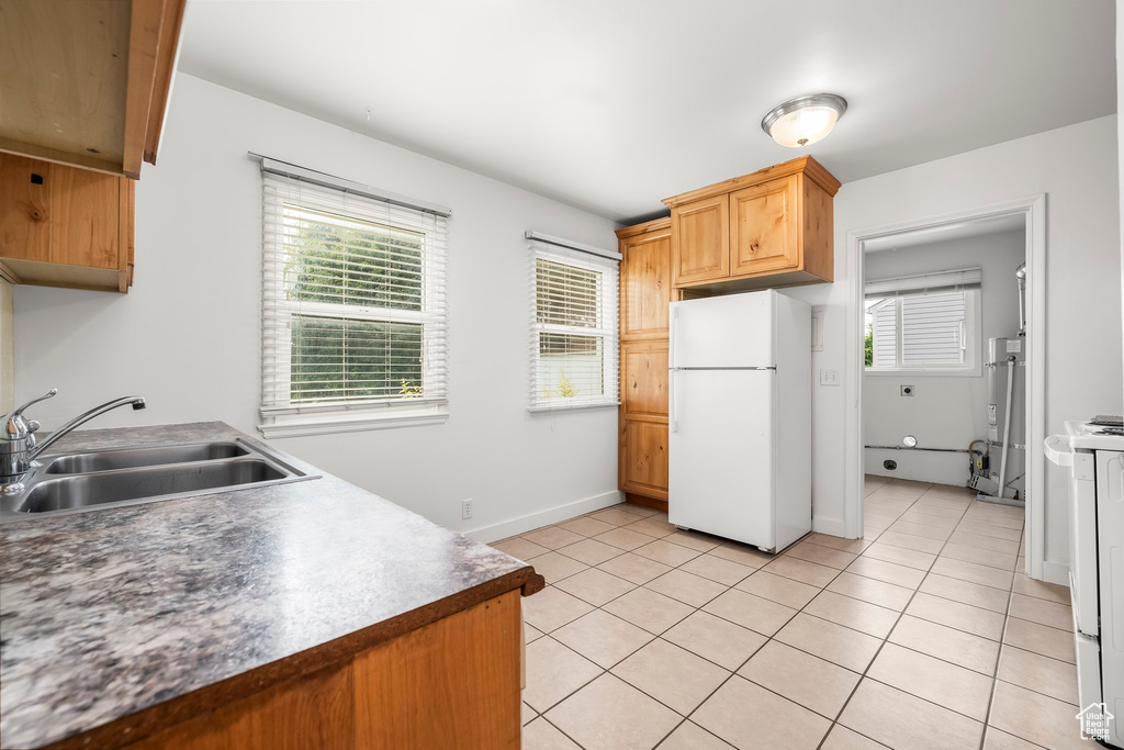 Kitchen featuring sink, light tile patterned floors, and white appliances