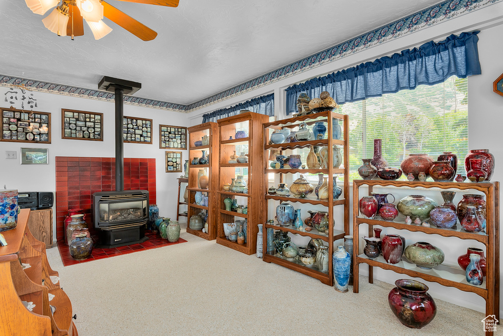 Miscellaneous room with a wood stove, carpet floors, and ceiling fan