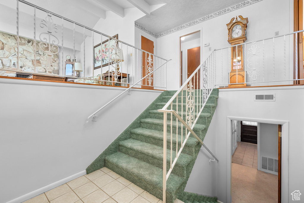 Stairs with beam ceiling and tile patterned flooring