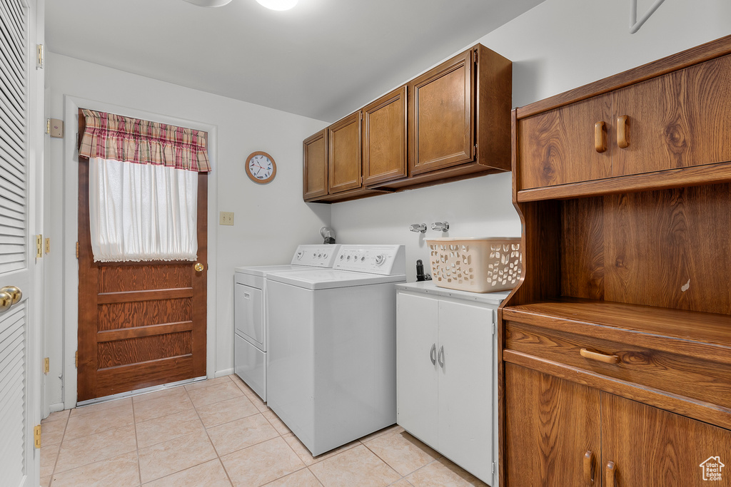 Laundry area with cabinets, washer and dryer, and light tile patterned flooring