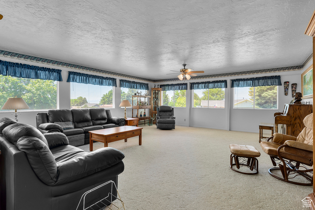 Carpeted living room with a textured ceiling and ceiling fan