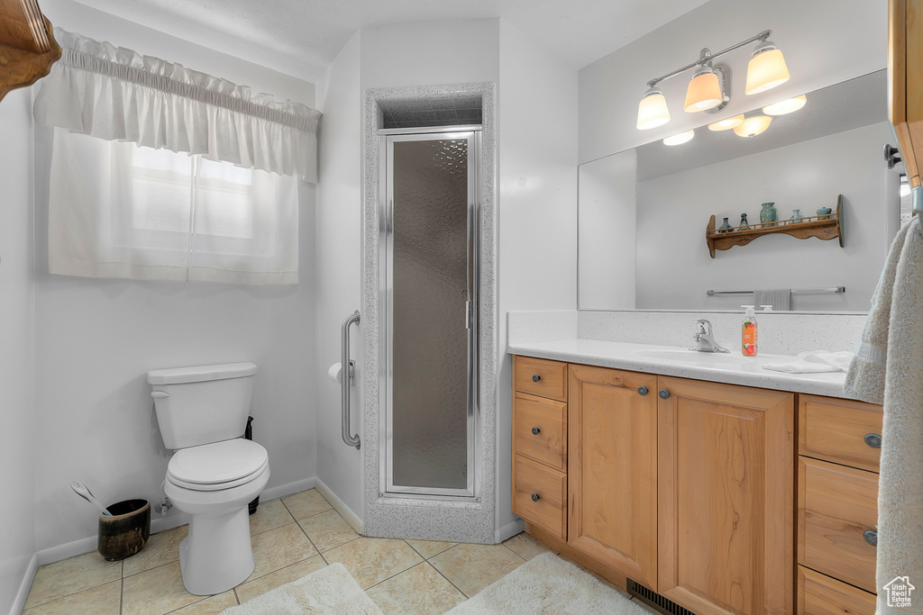 Bathroom featuring walk in shower, tile patterned flooring, toilet, and vanity