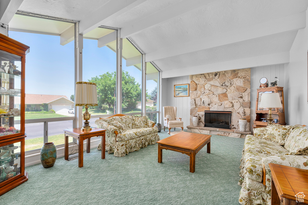 Living room featuring beamed ceiling, a healthy amount of sunlight, carpet flooring, and a fireplace