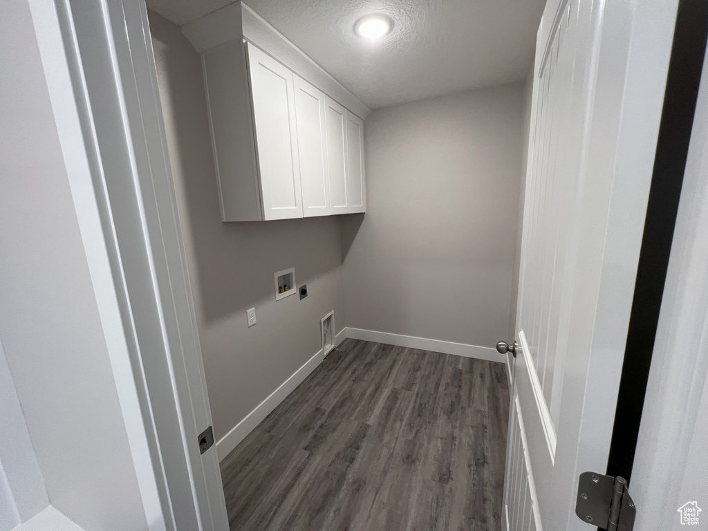 Washroom with cabinets, hookup for a washing machine, electric dryer hookup, and dark wood-type flooring