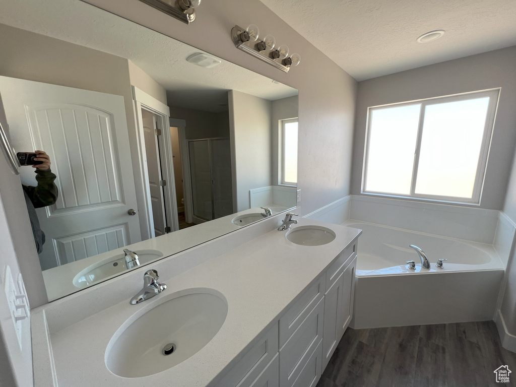 Bathroom featuring independent shower and bath, wood-type flooring, and dual bowl vanity