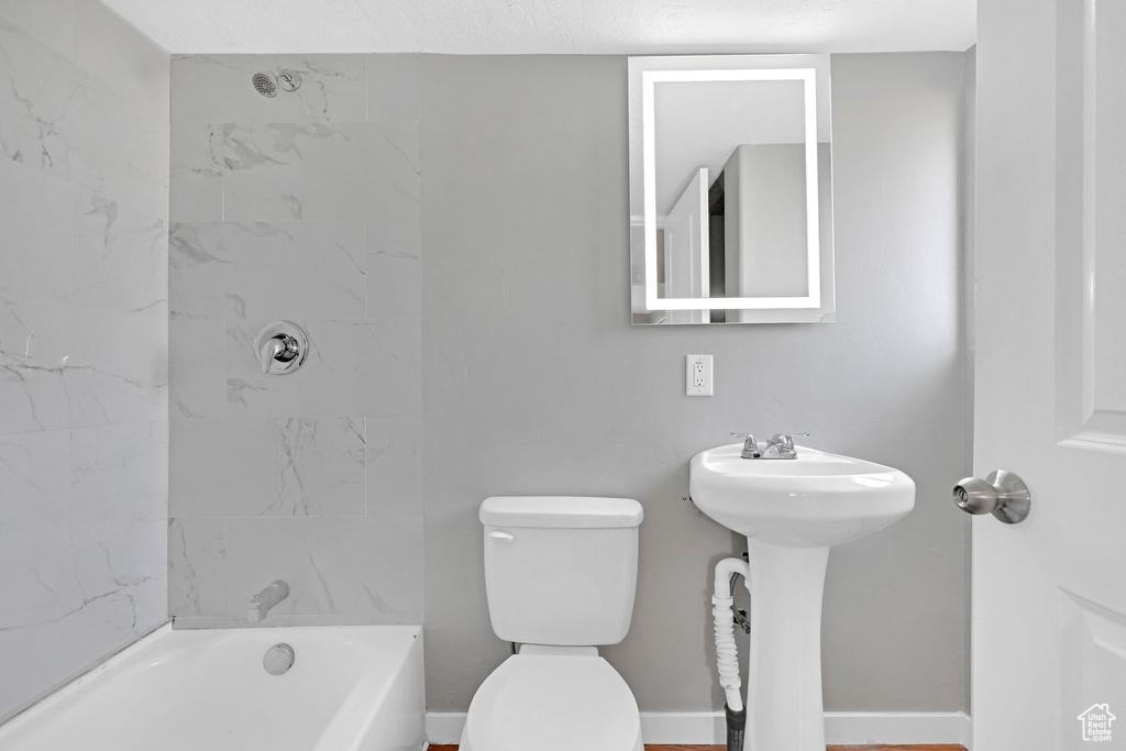 Bathroom featuring tiled shower / bath combo and toilet