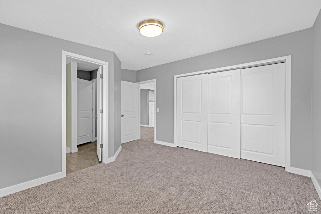 Unfurnished bedroom featuring light colored carpet and a closet