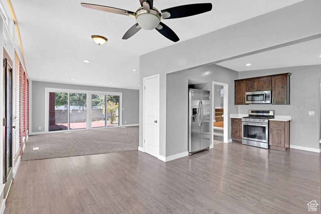 Kitchen with appliances with stainless steel finishes, carpet floors, ceiling fan, and dark brown cabinetry