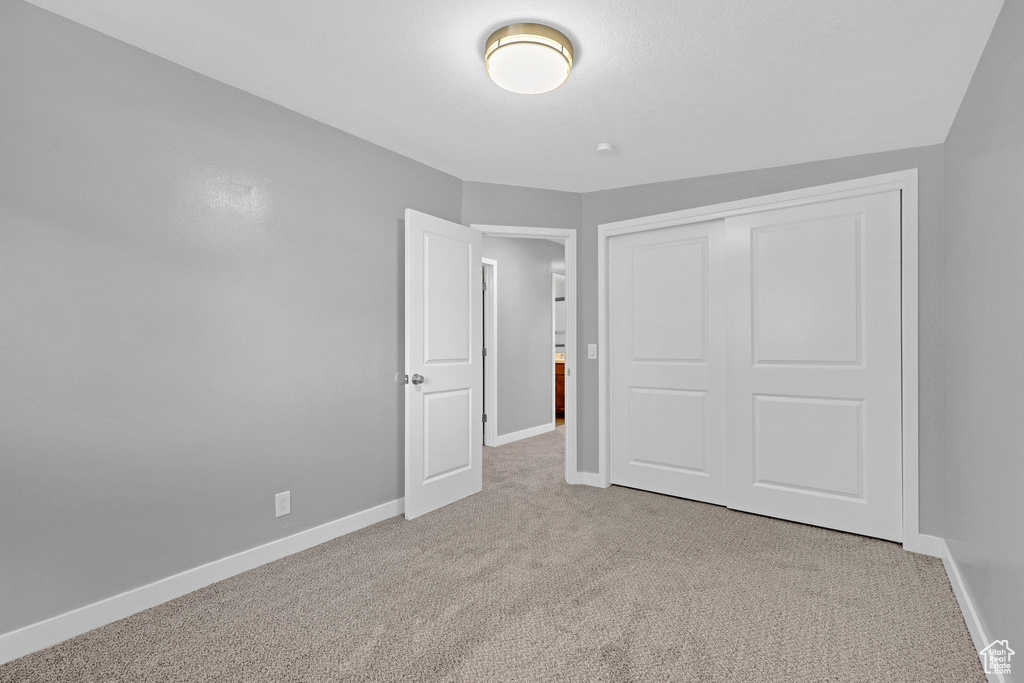 Unfurnished bedroom with light carpet and a closet