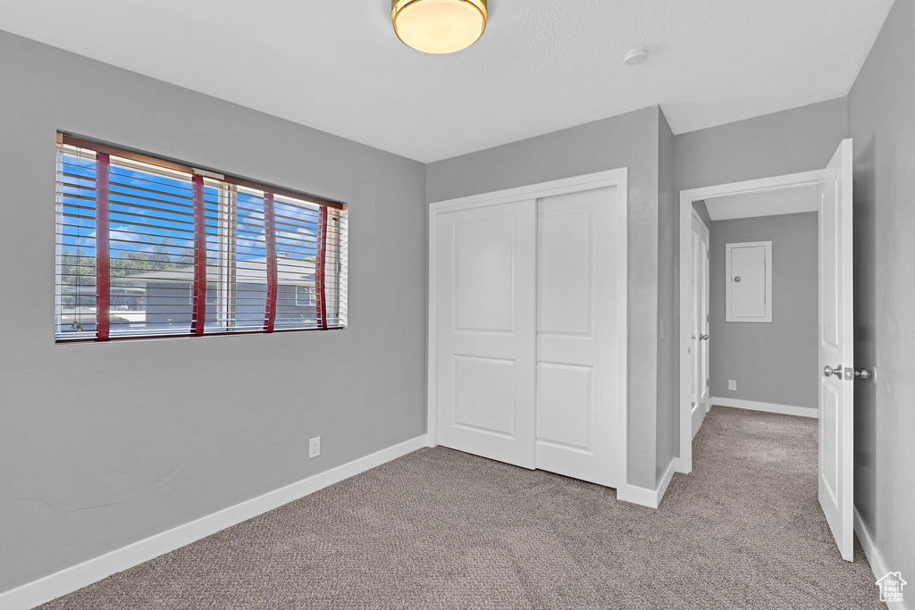 Unfurnished bedroom featuring light carpet and a closet