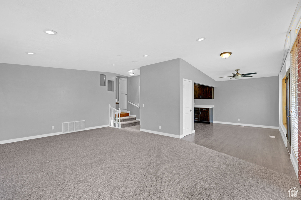 Unfurnished living room featuring vaulted ceiling, carpet floors, and ceiling fan