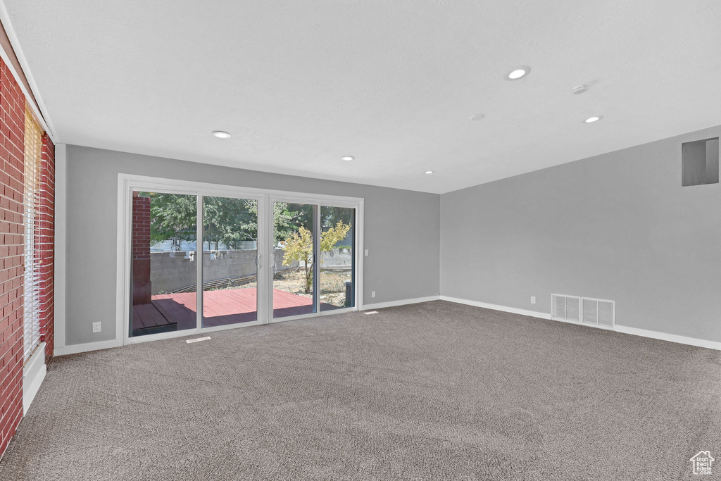 Empty room featuring brick wall and carpet