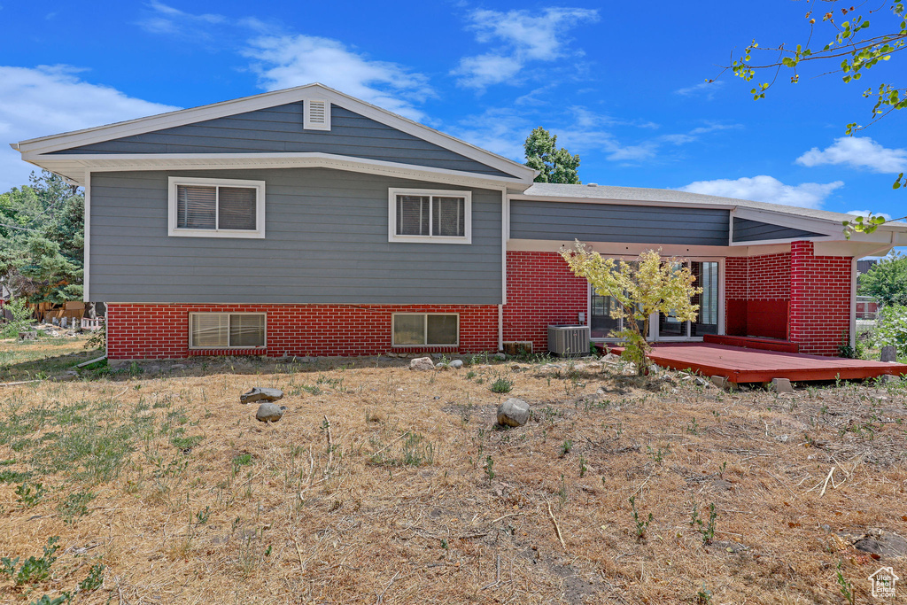 Back of property with a wooden deck and central AC unit