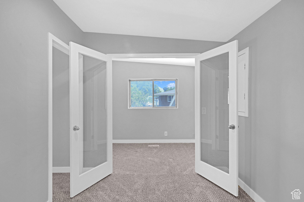 Interior space with carpet floors, french doors, and vaulted ceiling