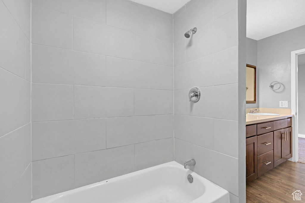 Bathroom with hardwood / wood-style flooring, vanity, and tiled shower / bath