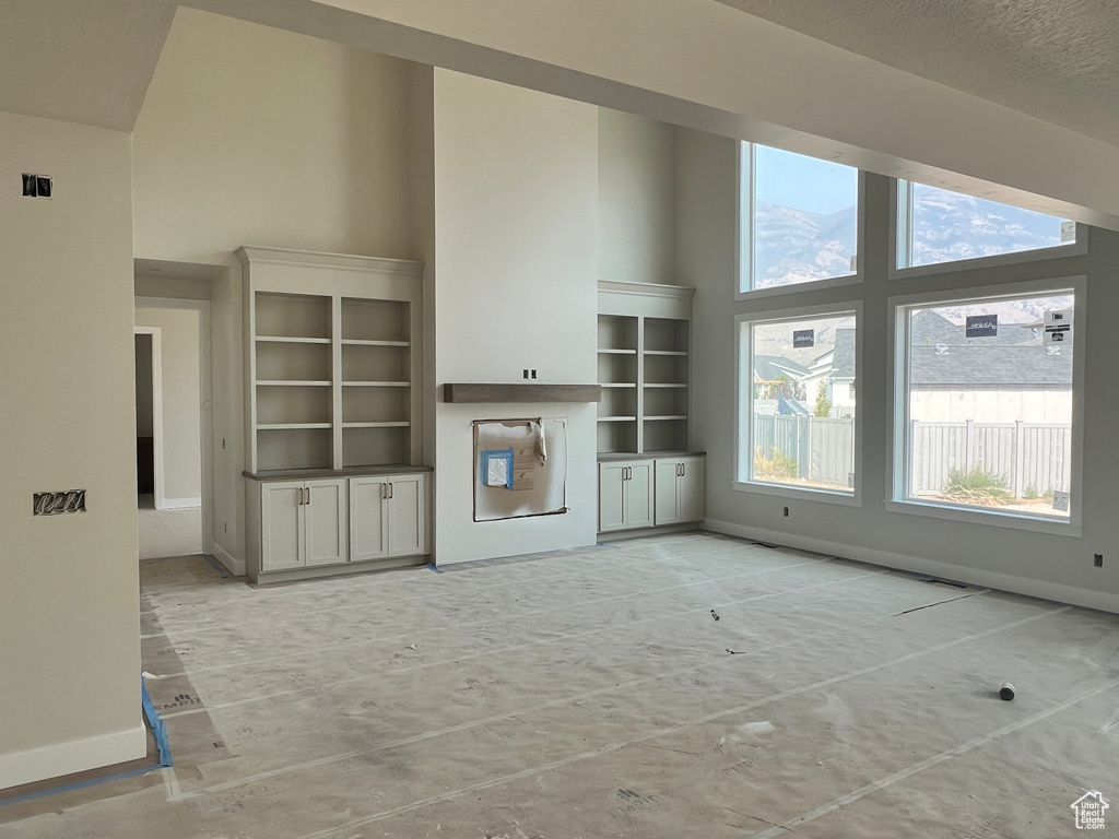 Unfurnished living room featuring a towering ceiling and a textured ceiling