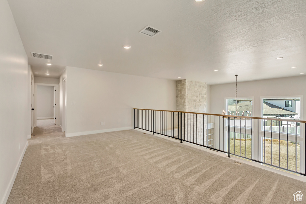 Spare room featuring a chandelier, a textured ceiling, and light colored carpet