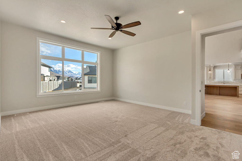 Carpeted spare room with ceiling fan and sink