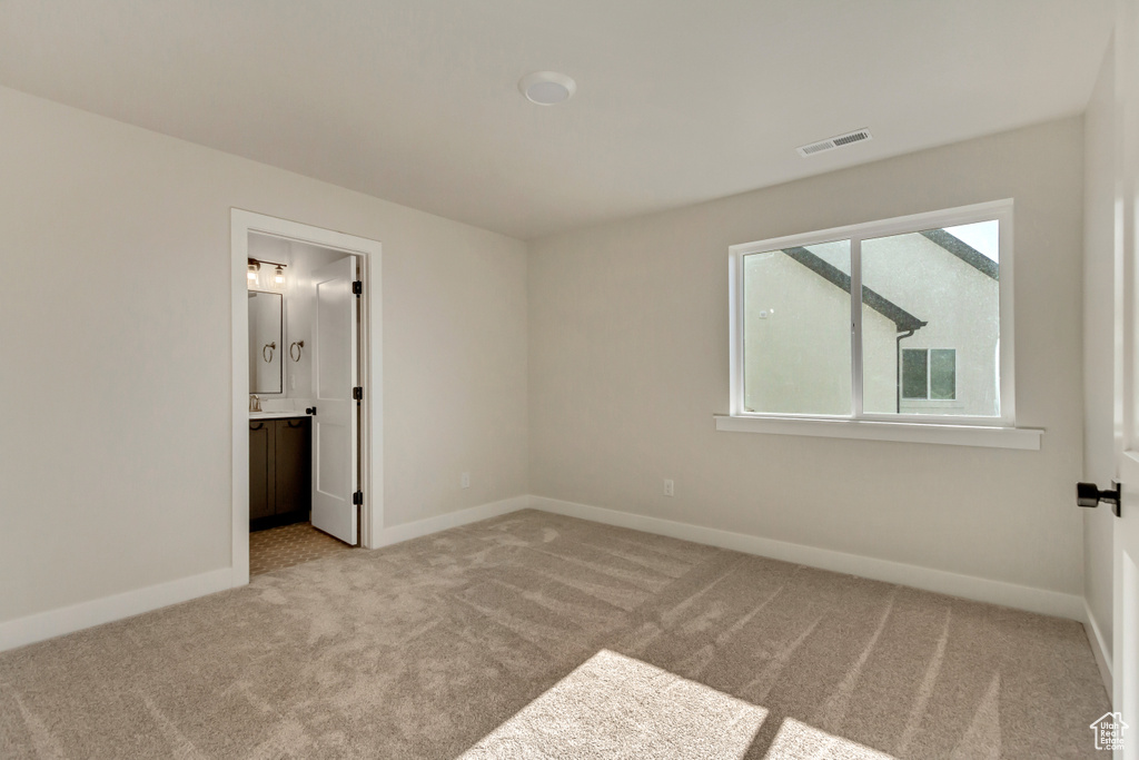 Unfurnished bedroom featuring light carpet and ensuite bath