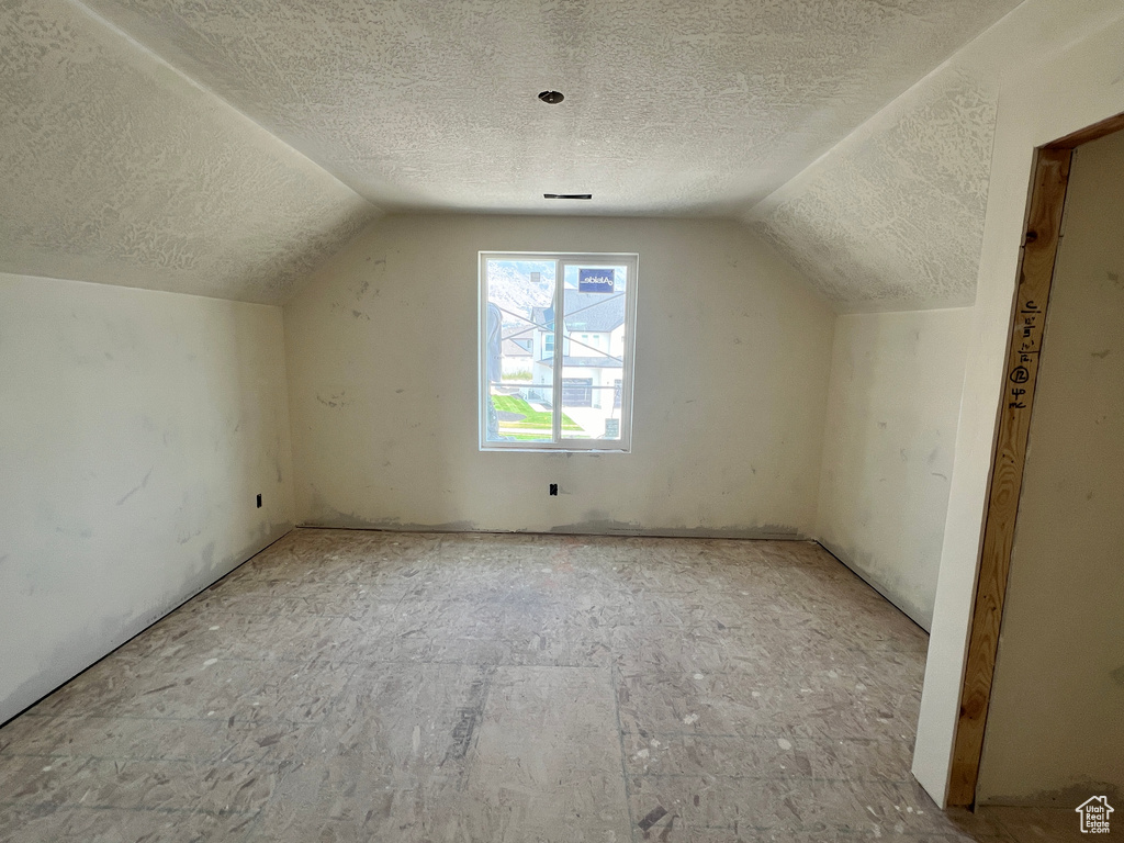 Bonus room featuring lofted ceiling and a textured ceiling