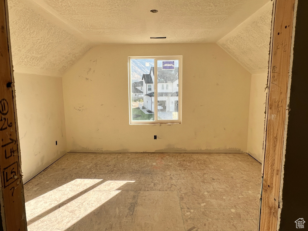 Additional living space featuring a textured ceiling and vaulted ceiling