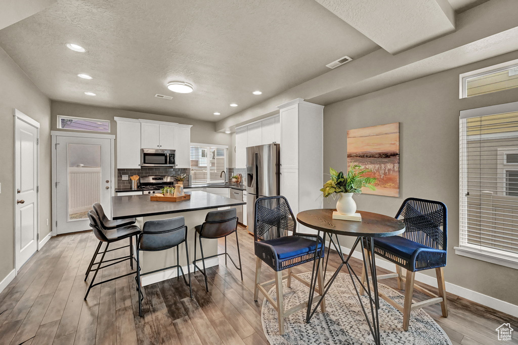 Kitchen featuring white cabinets, a textured ceiling, hardwood / wood-style flooring, and stainless steel appliances