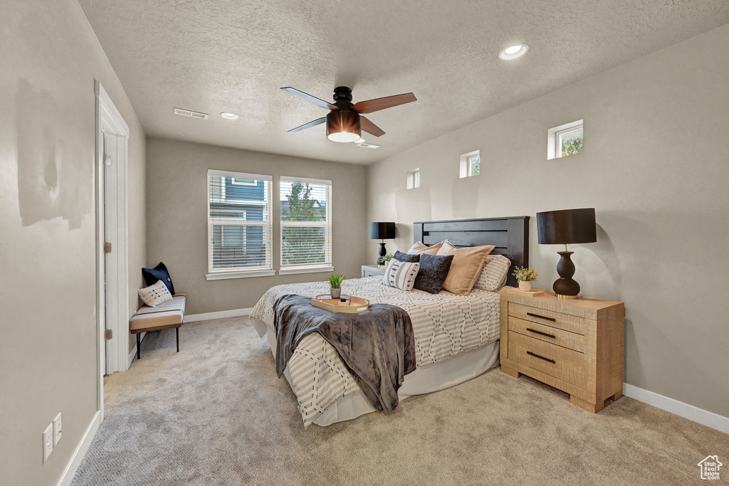 Carpeted bedroom with a textured ceiling and ceiling fan