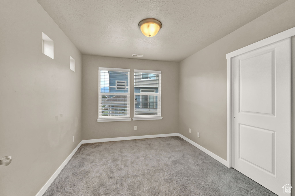 Spare room with a textured ceiling and light colored carpet