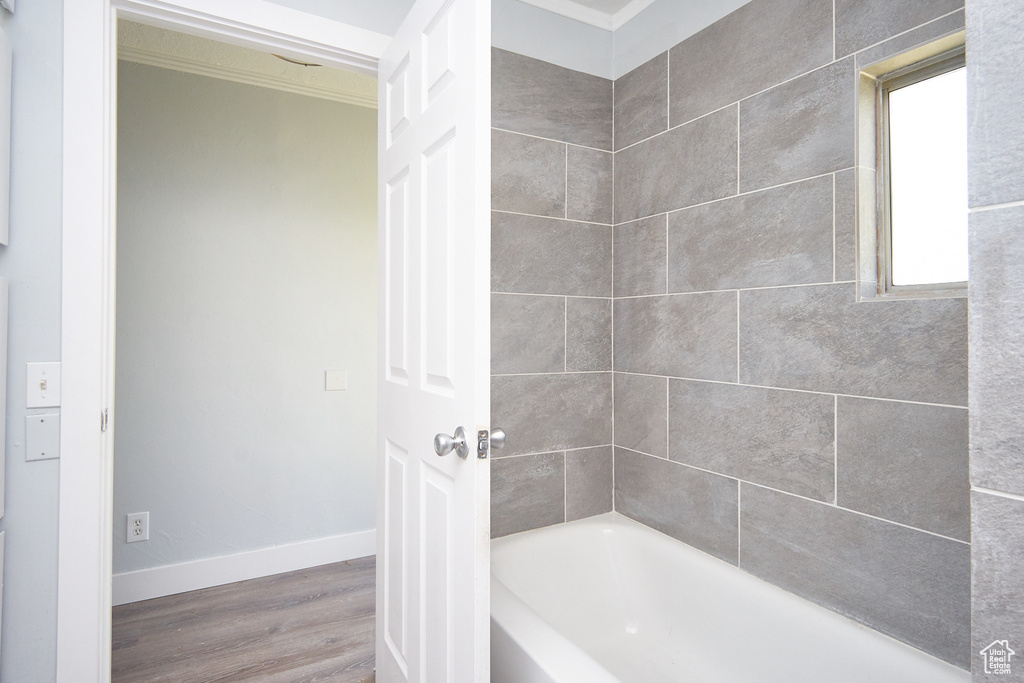 Bathroom featuring tiled shower / bath, hardwood / wood-style flooring, and crown molding