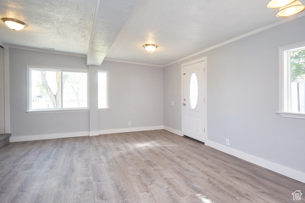 Entrance foyer featuring crown molding, a textured ceiling, and wood-type flooring