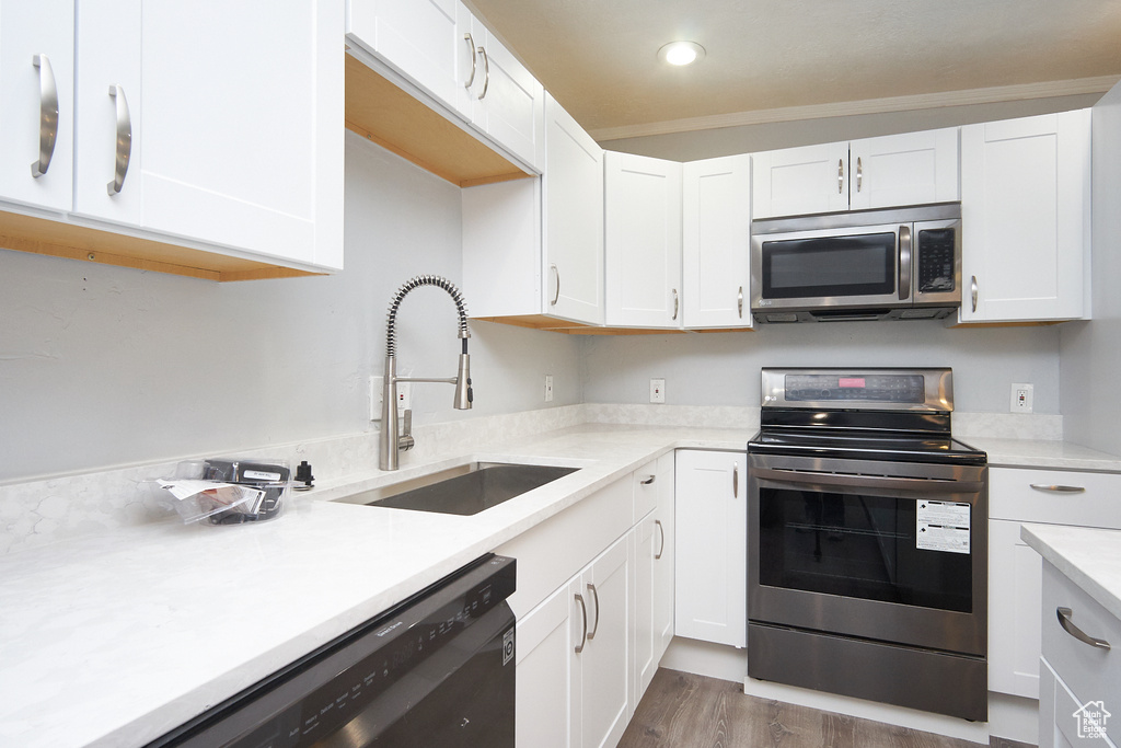 Kitchen featuring sink, appliances with stainless steel finishes, light wood-type flooring, and white cabinetry