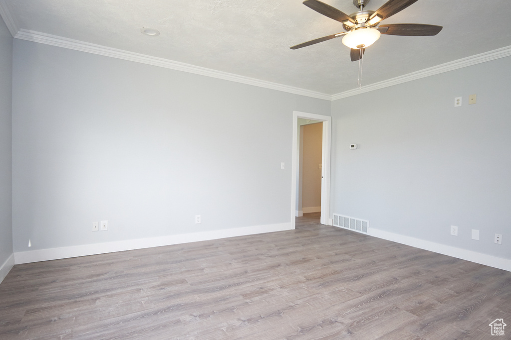 Empty room featuring hardwood / wood-style flooring, crown molding, and ceiling fan