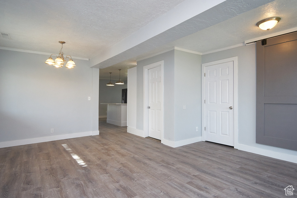 Spare room featuring hardwood / wood-style flooring, crown molding, a barn door, and a textured ceiling