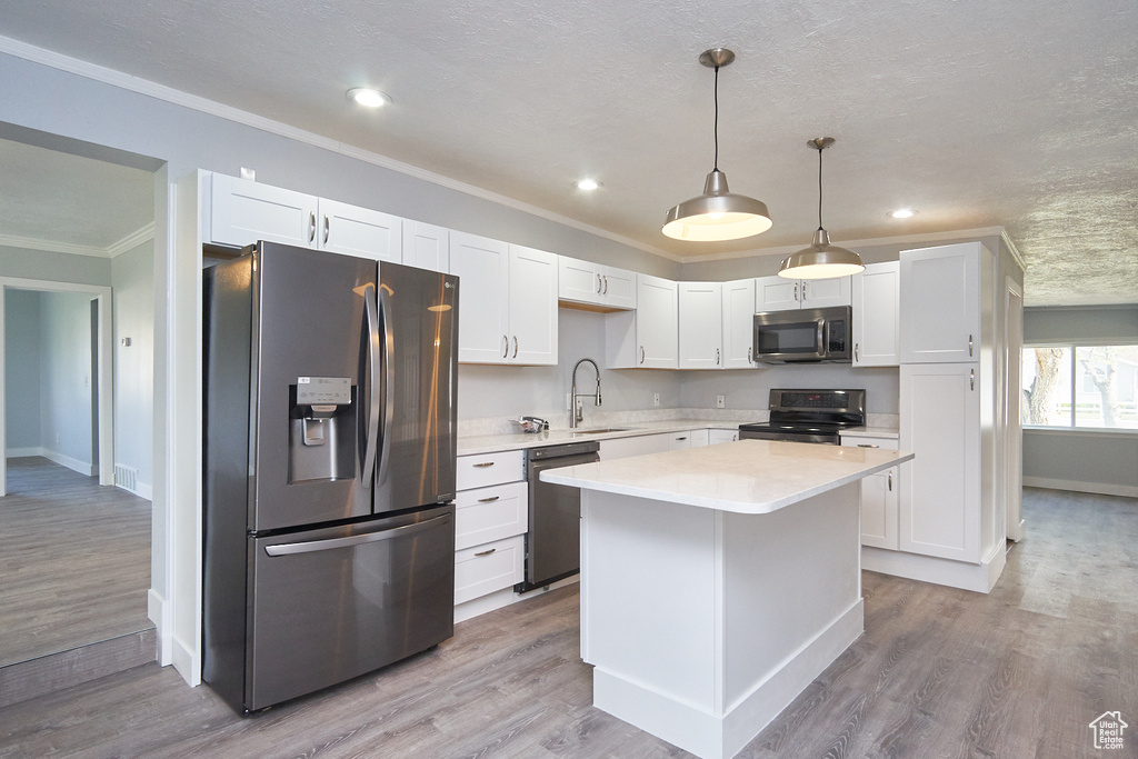 Kitchen featuring light wood-type flooring, hanging light fixtures, stainless steel appliances, and white cabinets