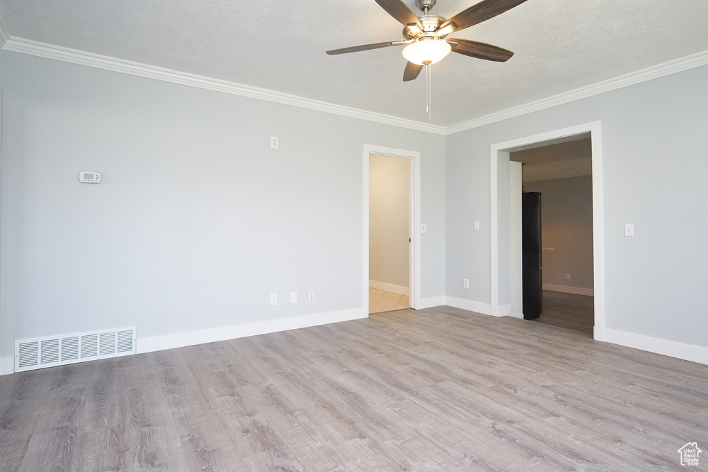 Empty room with wood-type flooring, ceiling fan, and crown molding