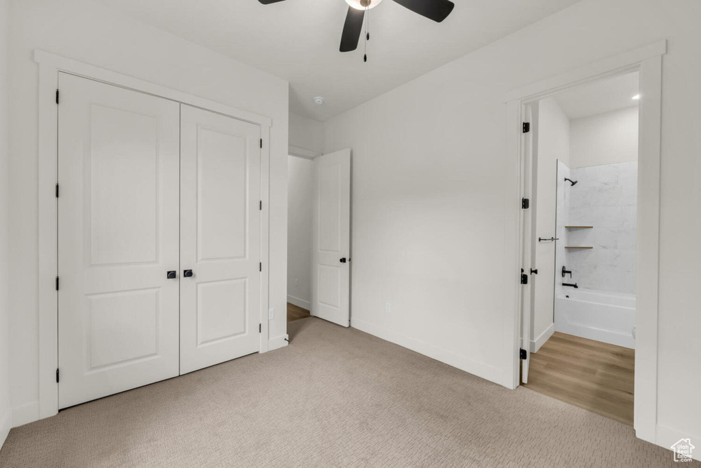 Unfurnished bedroom featuring ensuite bathroom, light carpet, a closet, and ceiling fan