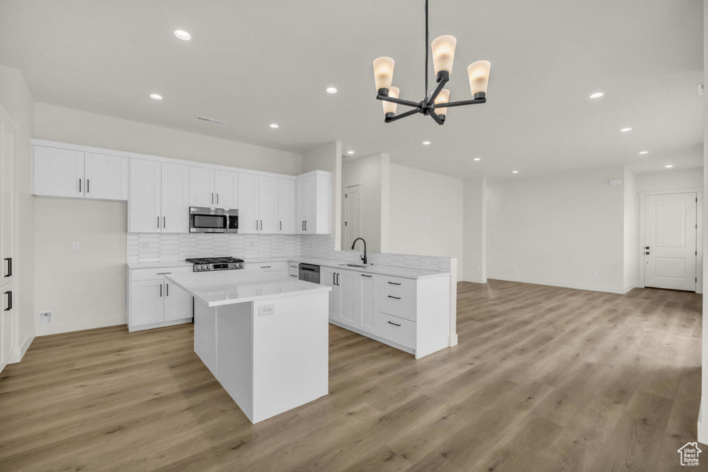 Kitchen featuring a kitchen island, stainless steel appliances, light hardwood / wood-style floors, decorative backsplash, and sink